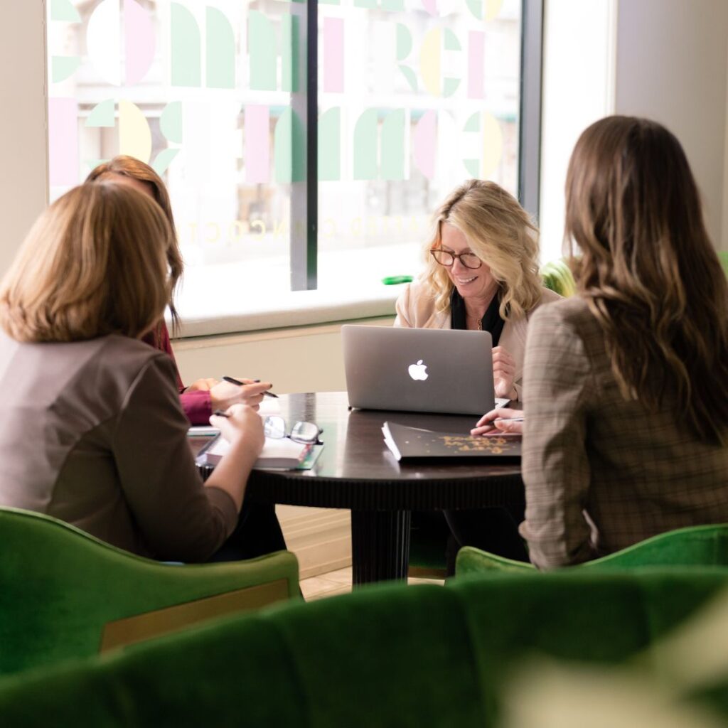 four women sit at a table to discuss how to build customer relationships